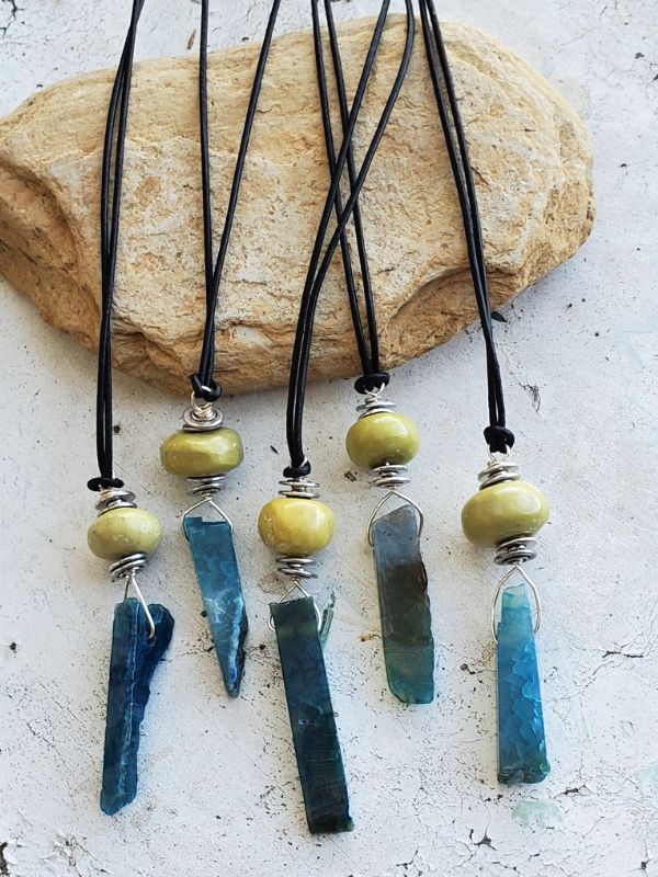 blue green gemstone stick necklaces on distressed white table