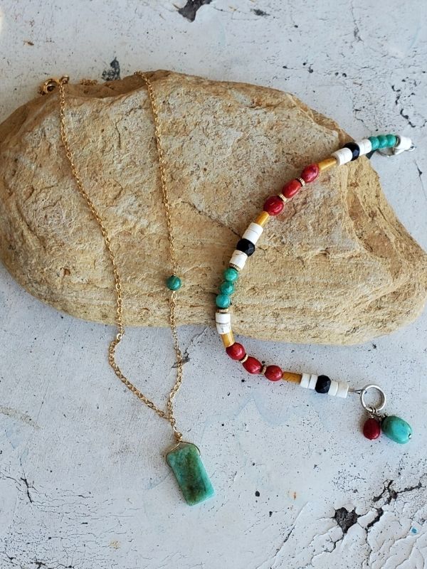 green gemstone necklace & colorful bracelet on rock