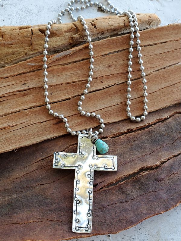 long silver cross necklace on wood