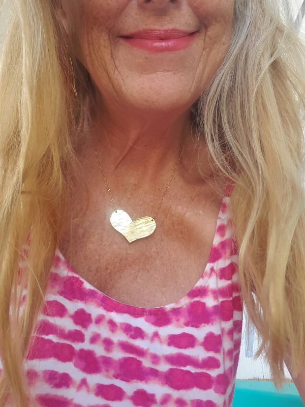 wearing pink and a gold heart necklace