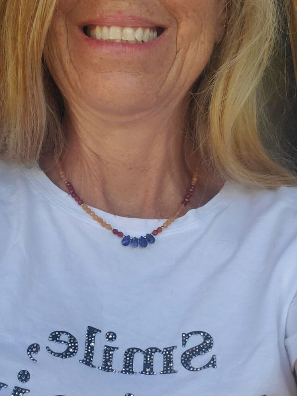female wearing blue, orange gemstone necklace