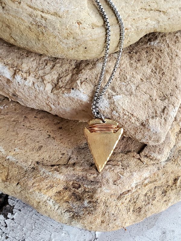 mixed metal arrowhead necklace on rock stack