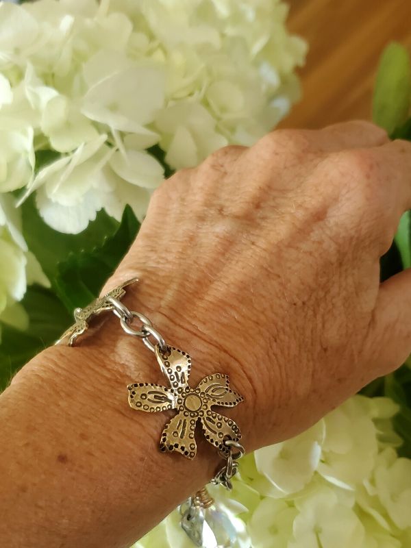 metal flower bracelet on wrist next to real flowers