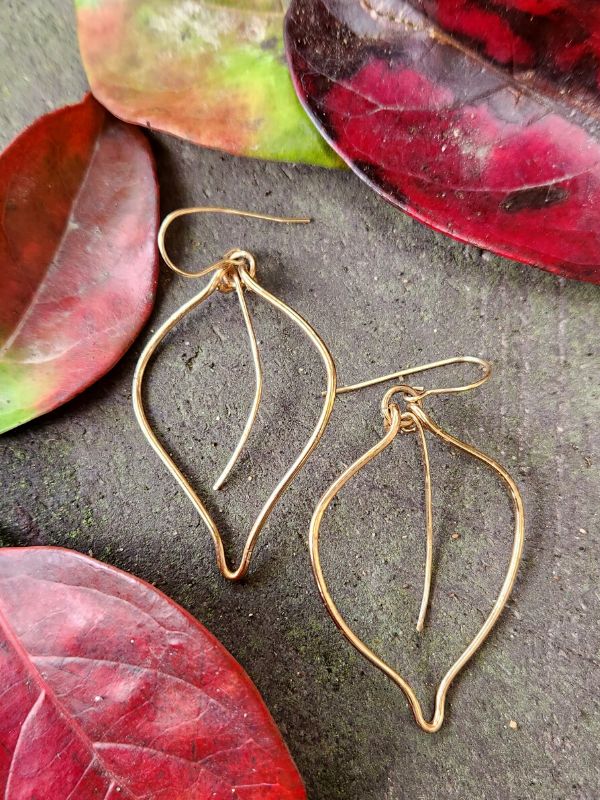 gold leaf outline earrings on display with real leaves