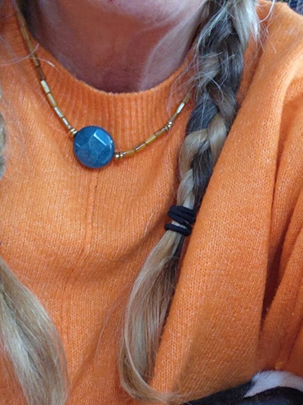orange sweater with blue button necklace