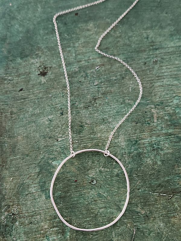 silver open circle chain necklace on green background