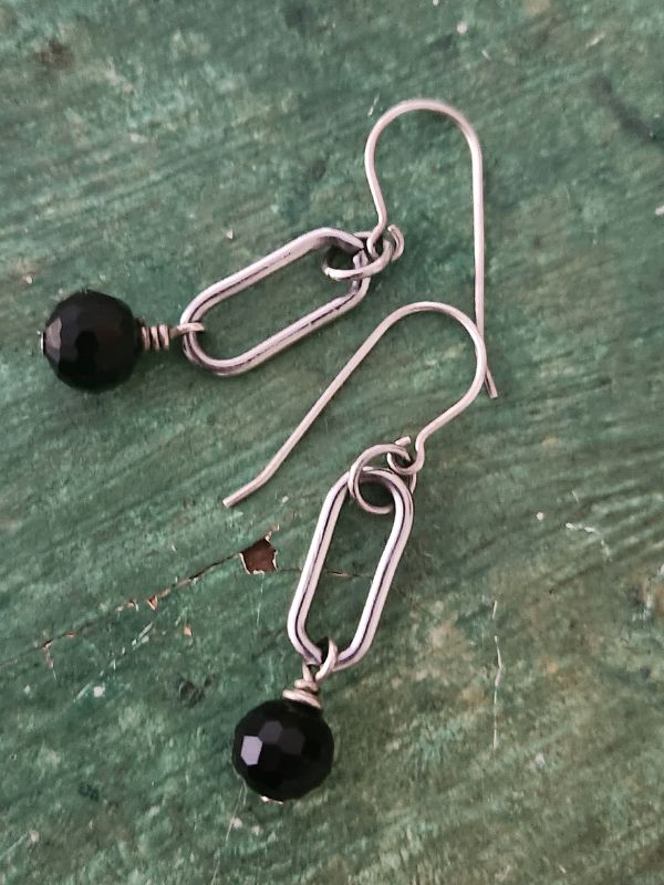 modern silver oval black gemstone earrings on green nnackground