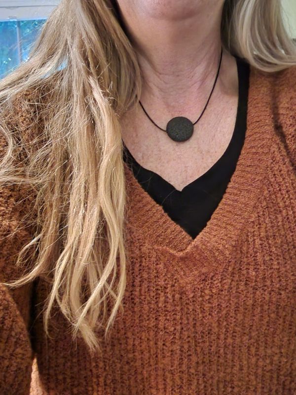 wearing black round stone necklace with brown sweater