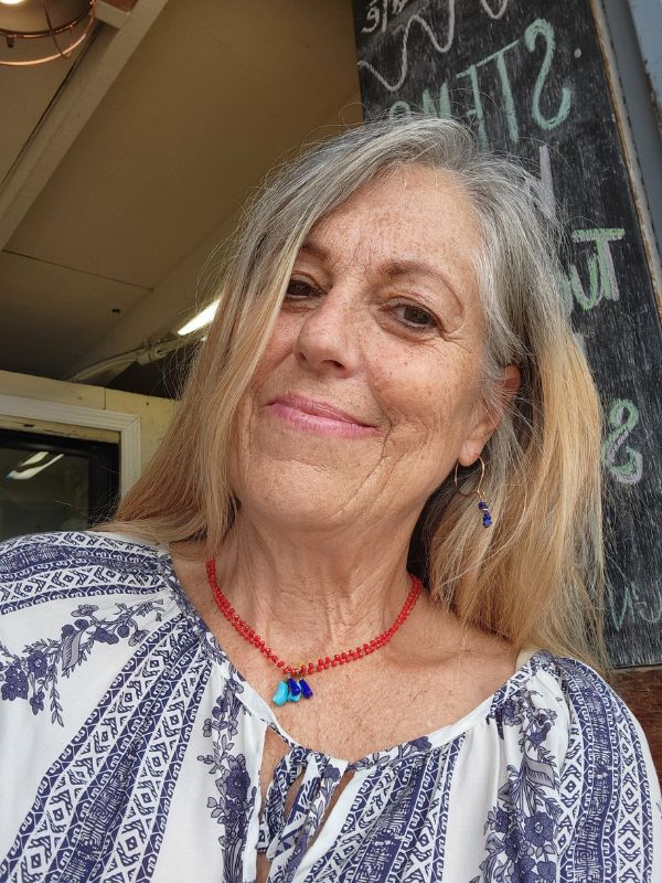 model wearing blue print top with red necklace