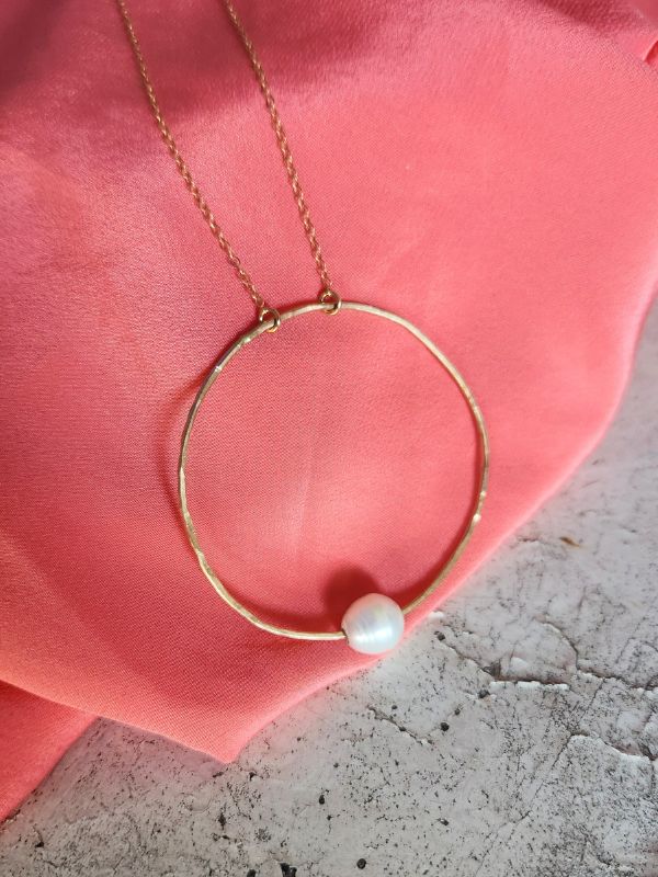 pink blouse gold circle white pearl necklace