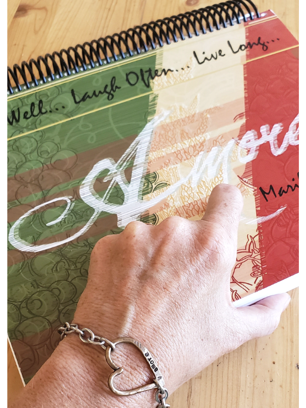 heart bracelet on wrist with cookbook
