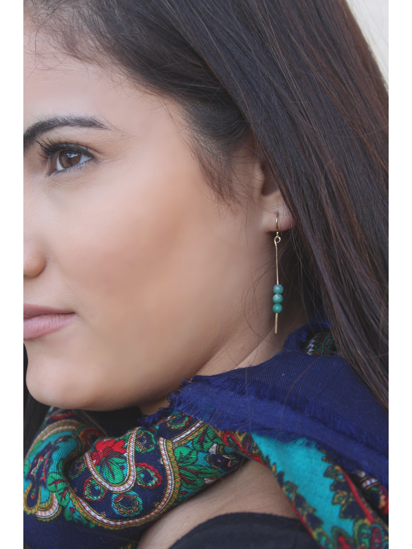 female with neck scarf and green gemstone earrings