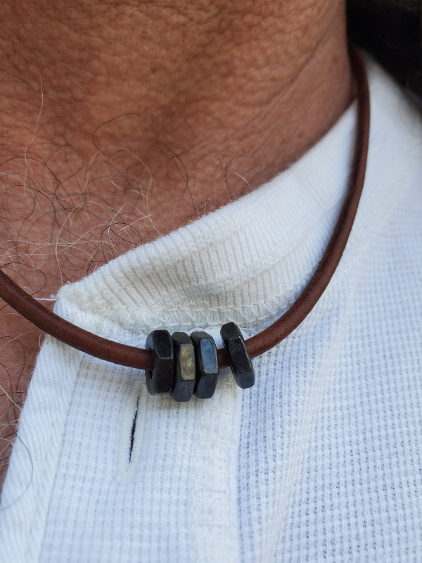 brown leather necklace on neck and white shirt