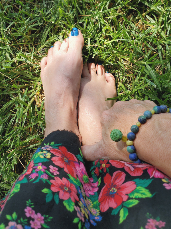 aromatherapy bracelet on arm with feet in the grass