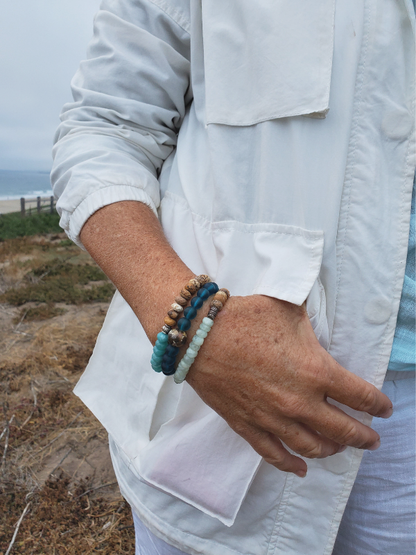 gemstone stack bracelets on arm with white jacket