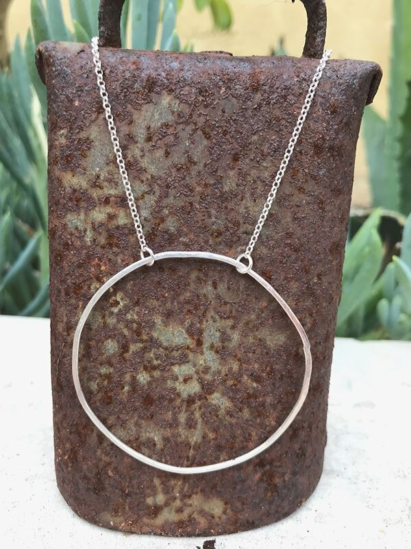 silver circle necklace on a rusted cowbell