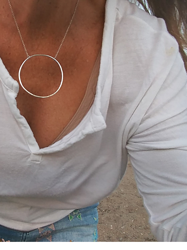big silver circle necklace worn with white top