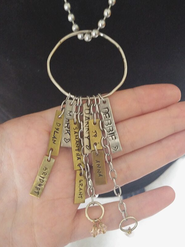 charm necklace and tags held in hand